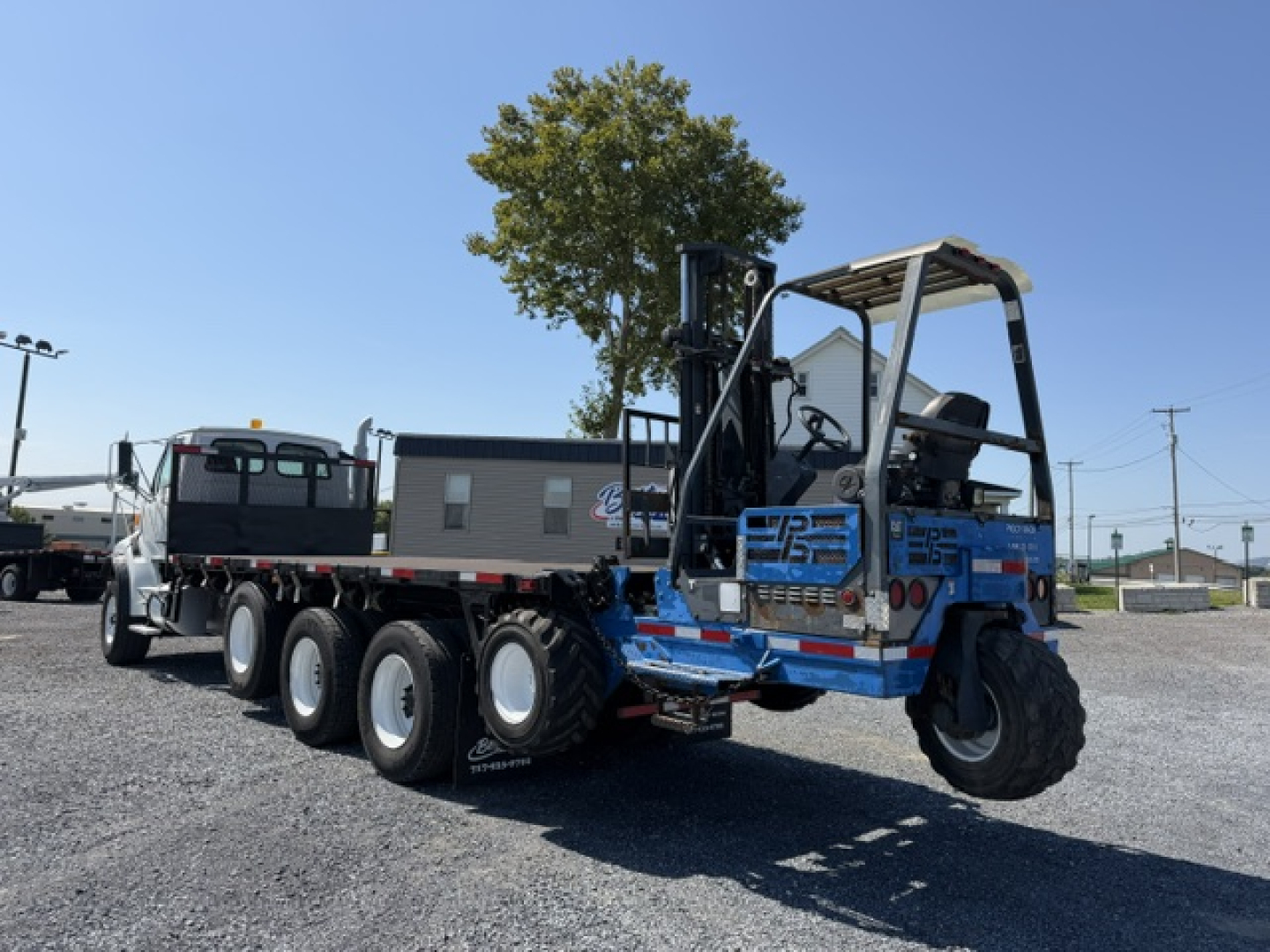 2006 Sterling LT9500 heavy flatbed truck with multiple rear axles and blue excavator-like attachment, viewed from rear-right side.