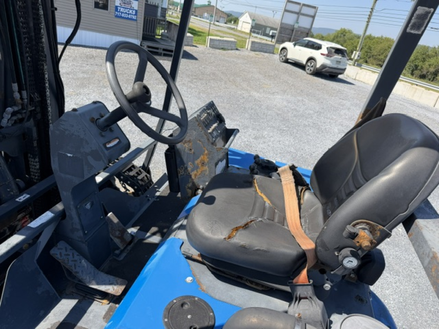 Operator seat and steering wheel of a blue Sterling LT9500 forklift or truck in-cab view showing seat with seatbelt, steering wheel, pedals, and control console.