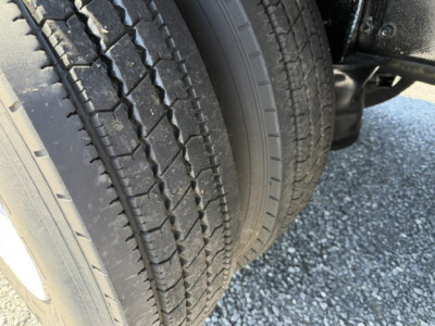 Truck image showing dual rear tires with tread and sidewalls visible in a parking lot.