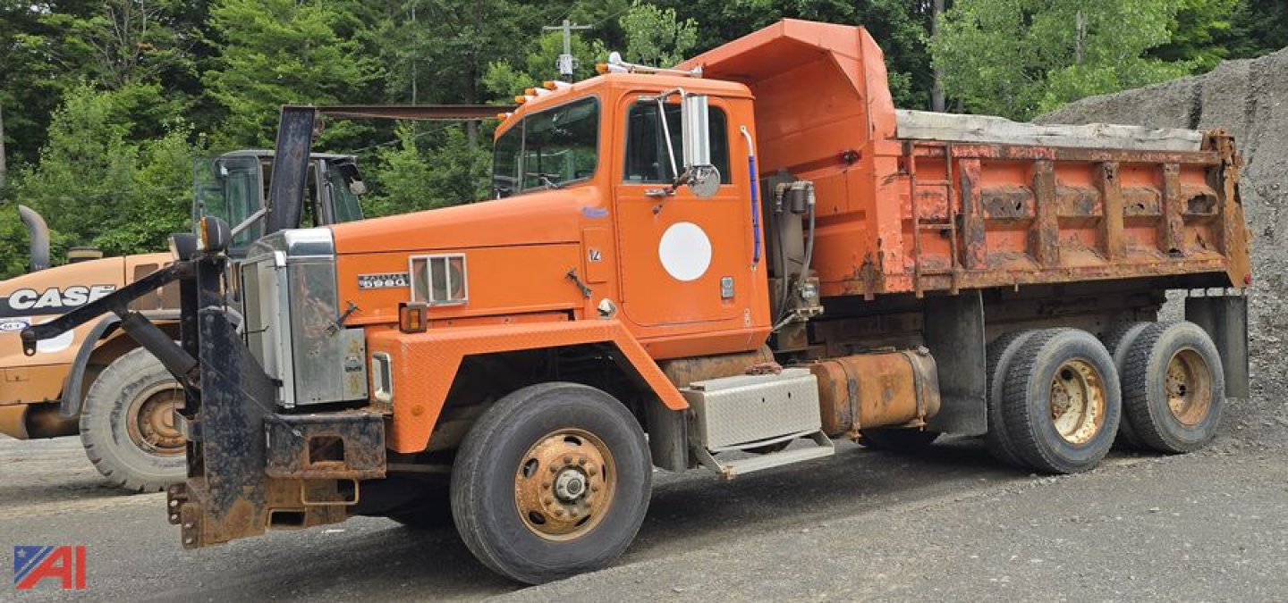 Dump truck side view showing orange 1998 International 5070 with open bed and front bumper, in-service vehicle with white circular logo on door.