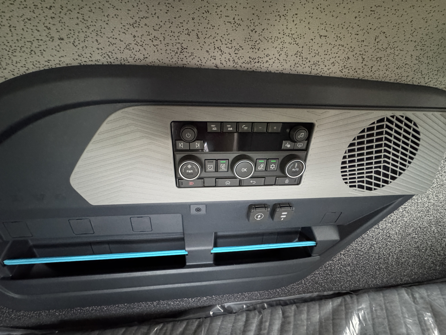 Cab overhead console and storage in a Volvo VNL truck showing control panel with climate buttons and a speaker grille, plus two blue-accented storage slots.