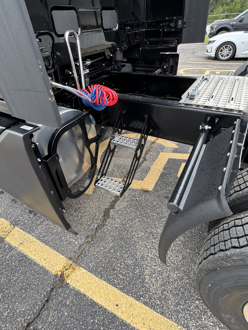  Volvo VNL64T860 tractor-trailer cab area showing steps and access ladder, air lines, and wiring near the fifth wheel mounting.