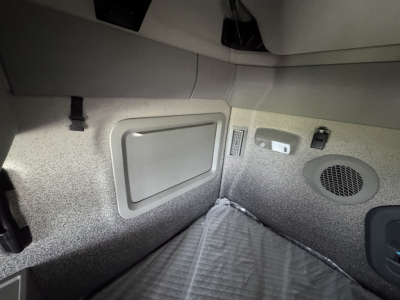 Volvo VNL64T860 sleeper cab interior corner showing storage hatch and speaker grill.
