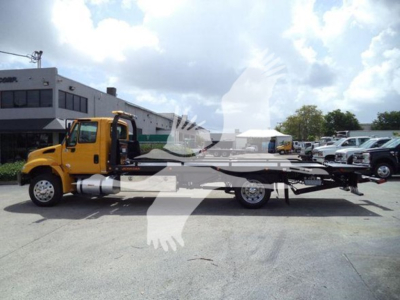 Truck mounted tow bed with yellow cab and long flatbed, side view showing rollback equipment and chassis.