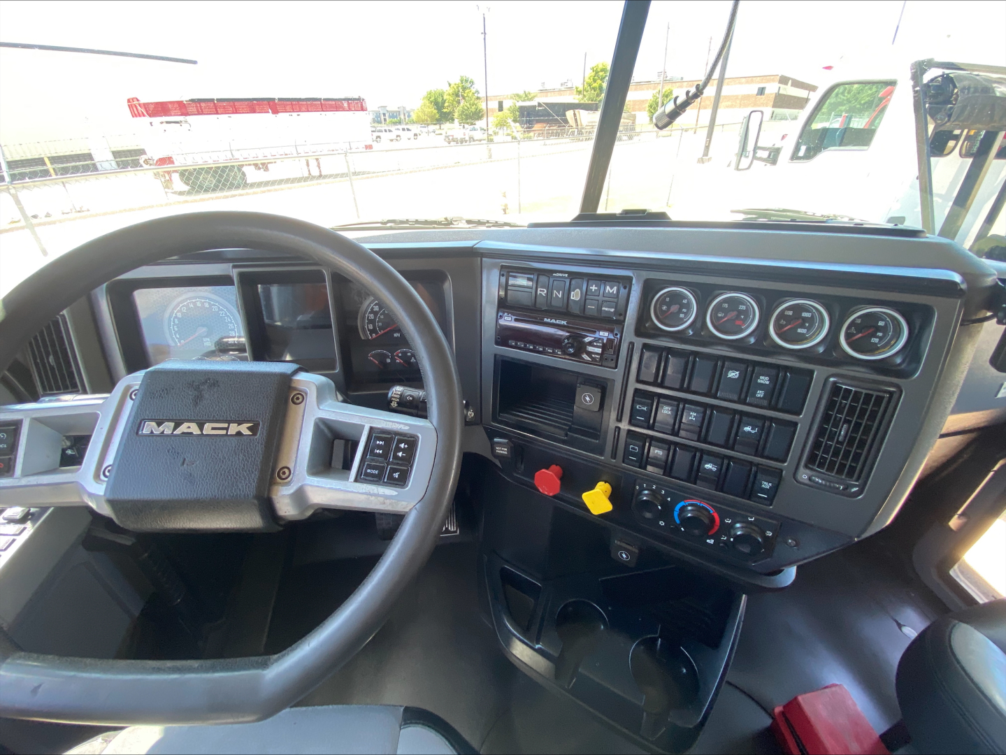 Mack PI64T interior showing steering wheel and dashboard gauges with multiple switches and controls.