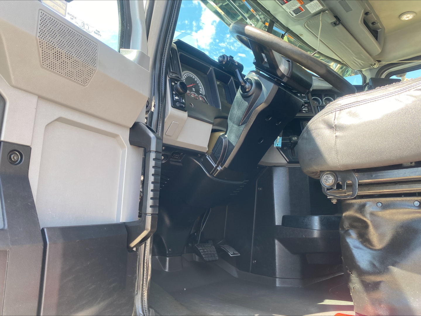 Cab interior of 2019 Mack PI64T truck showing steering wheel dashboard pedals and driver seat.
