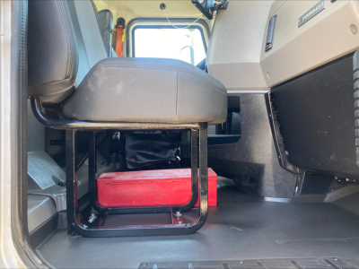 Cab interior of 2019 Mack PI64T conventional daycab showing driver seat with under-seat storage and red toolbox.