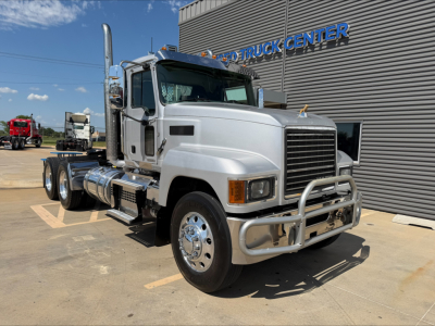Mack PI64T conventional daycab truck in-service showing front grille, chrome bumper guard, large exhaust stack, and dual rear axles.