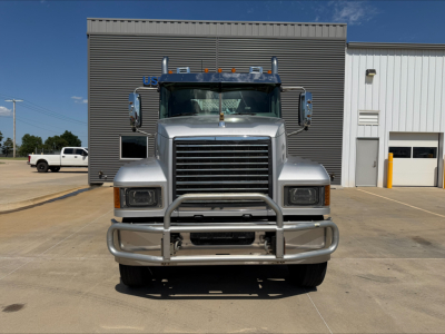 Mack PI64T conventional daycab truck front view showing chrome grille, bumper guard, large headlights, and mirrors.