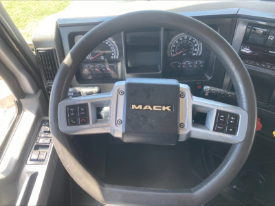 Mack PI64T truck interior steering wheel with gauges and control stalks visible; center of wheel shows 'MACK' badge.