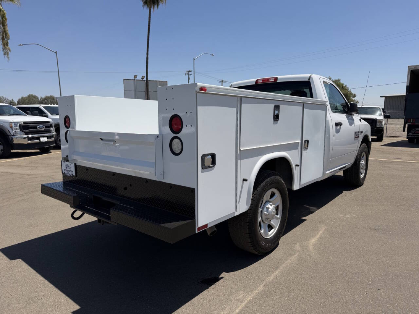 Ram 2500 service body truck in a parking lot, side and rear view showing utility boxes, black bumper, and white cab.