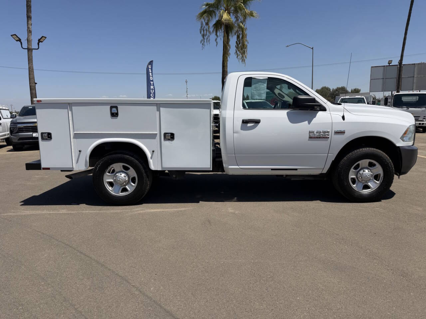 White 2015 Ram 2500 service utility truck with utility bed side compartments, driver side view.