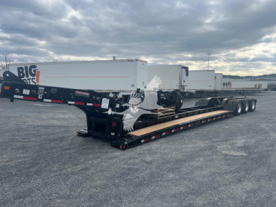 Lowboy trailer with multiple axles and a Fontaine Magnitude 55H-Dsr model, shown in an outdoor yard with other trailers in background.