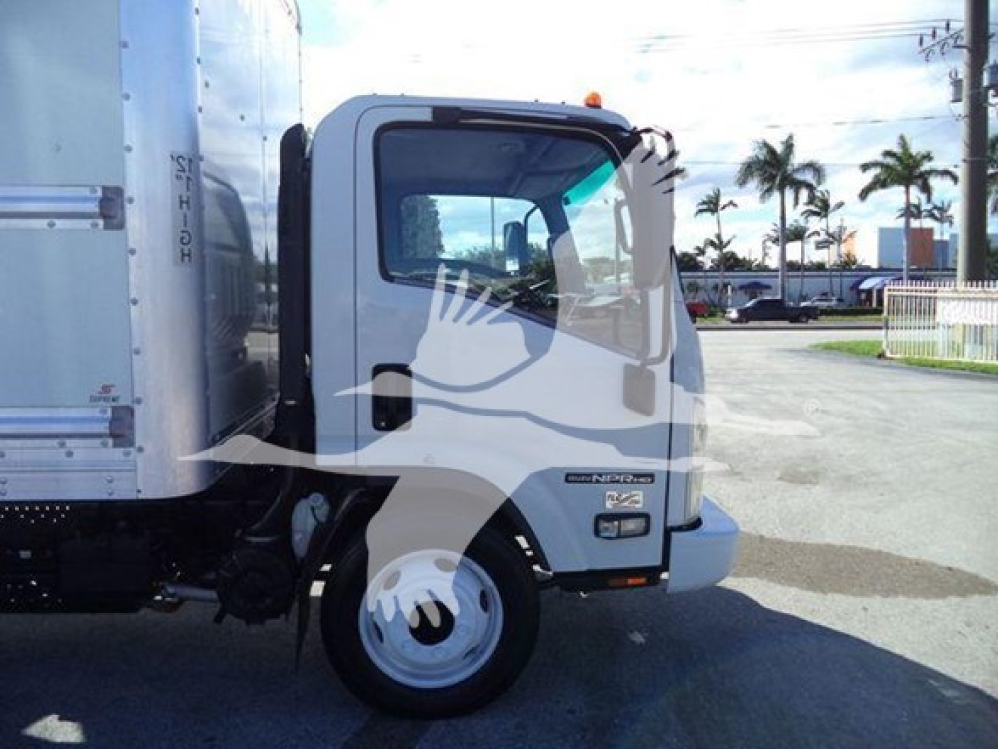Isuzu NPR HD box truck cab side view showing Isuzu emblem and NRR emblem on door, front wheel, and cargo box trailer;Text not legible but indicates 2019 Isuzu NPR HD.