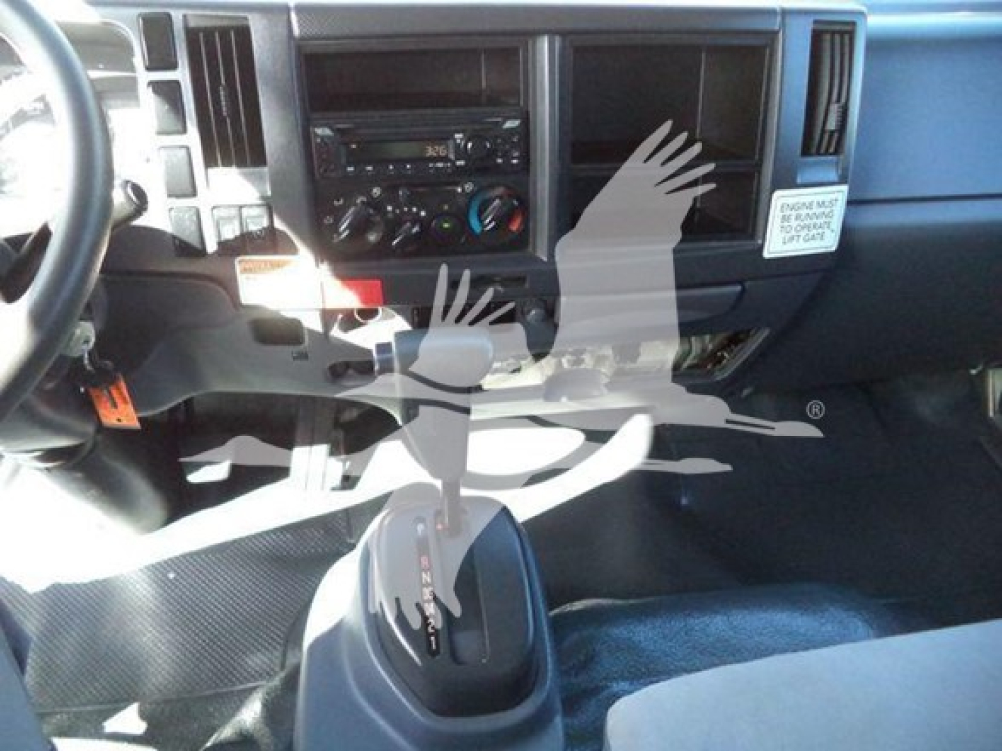 Isuzu NPR HD truck interior dashboard and gear shifter showing center console with radio, climate controls, and air vents.