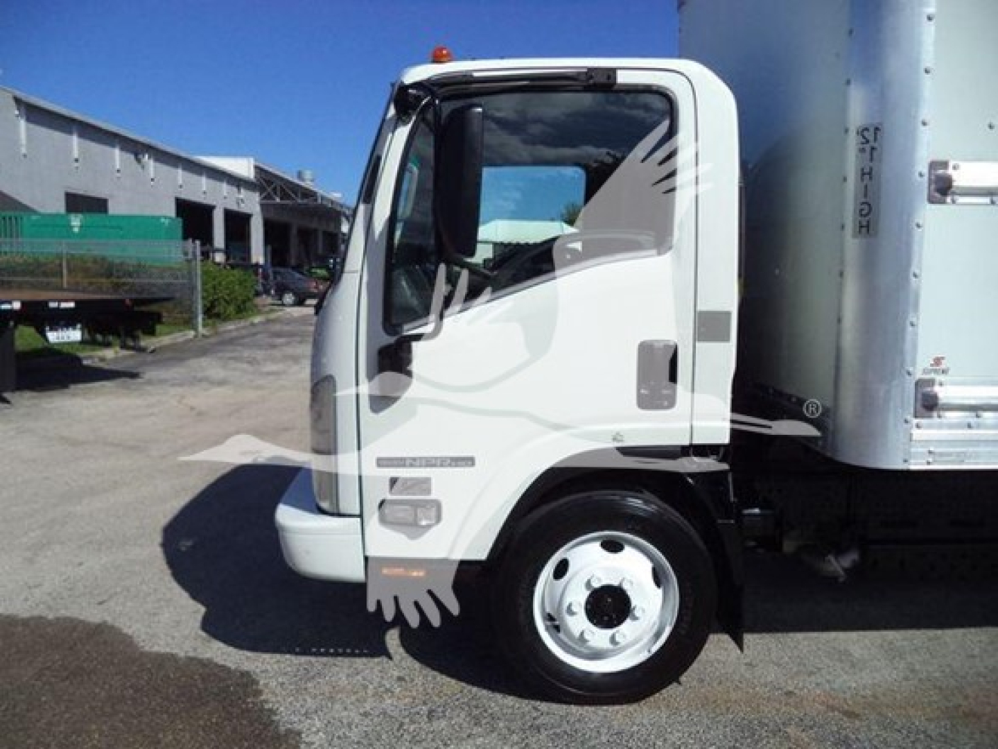 Isuzu NPR HD truck cab side view showing front wheel and part of box body with white paint.