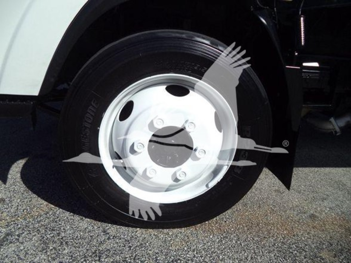 Isuzu NPR HD truck front wheel and fender showing steel wheel and tire with hubcap.