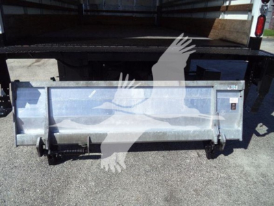 Isuzu NPR HD truck bed showing silver tailgate/box with latching mechanism and hydraulic hitch components.