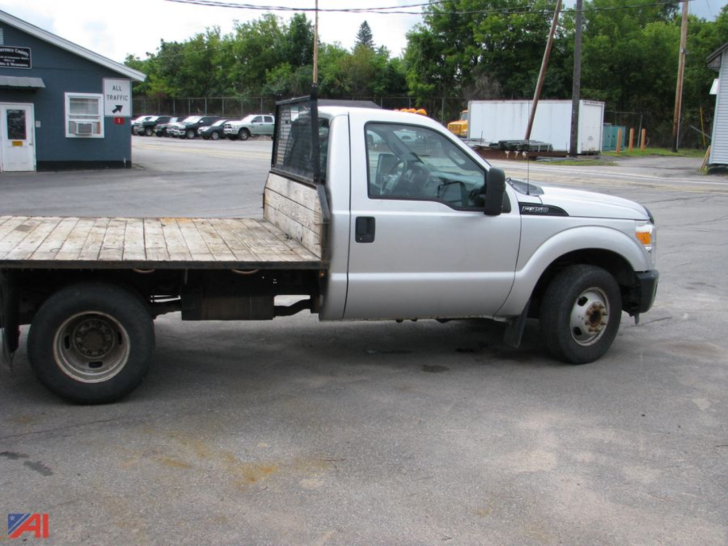Ford F-350 Super Duty flatbed truck with dual rear wheels, silver cab, flatbed wood deck, side view showing cab and bed.