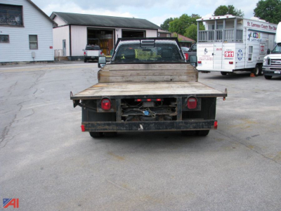 Truck flatbed rear view showing dual rear wheels and wooden bed with taillights.