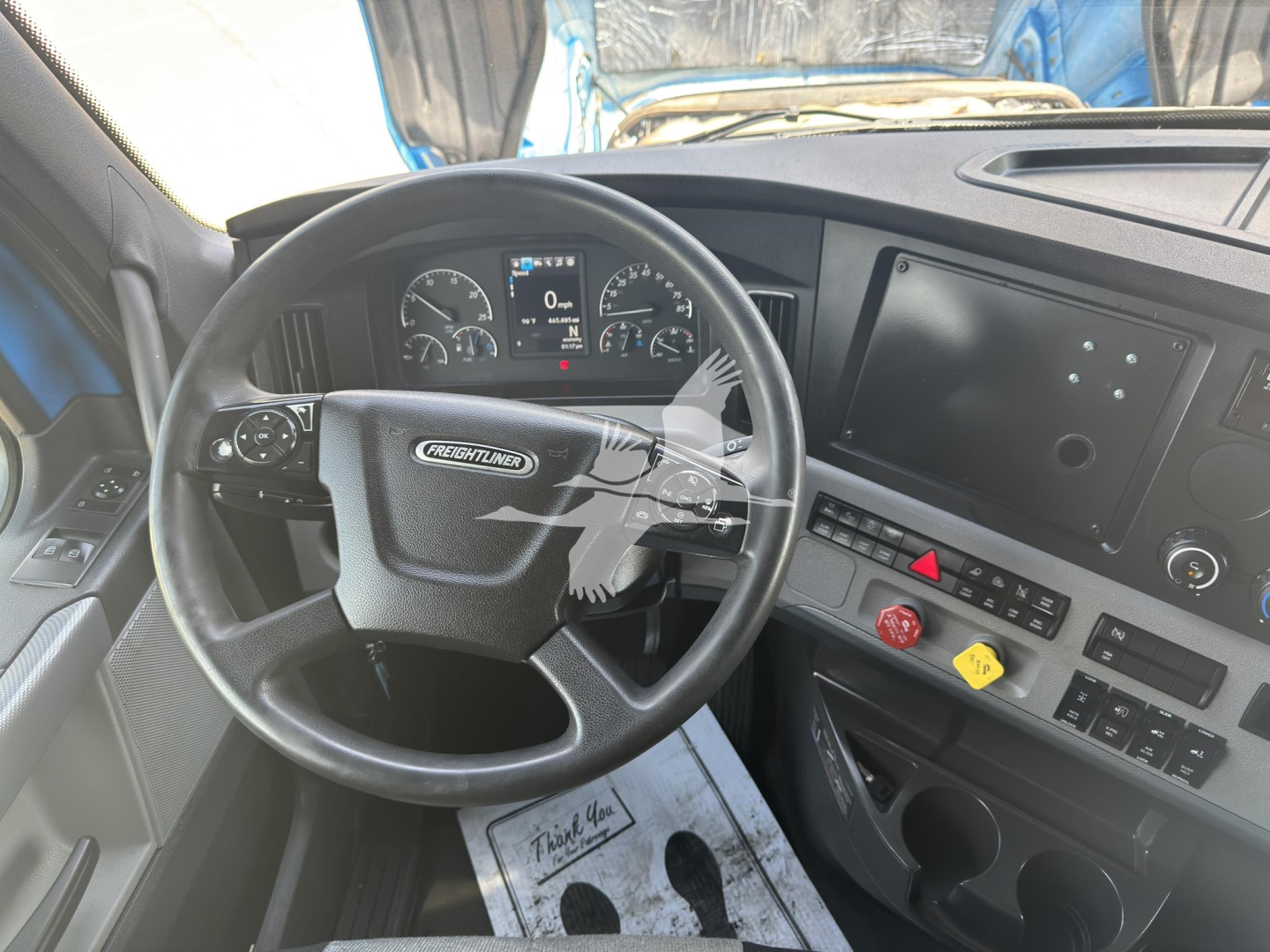 Freightliner Cascadia truck interior showing steering wheel and dashboard with instrument cluster and touchscreen display.
