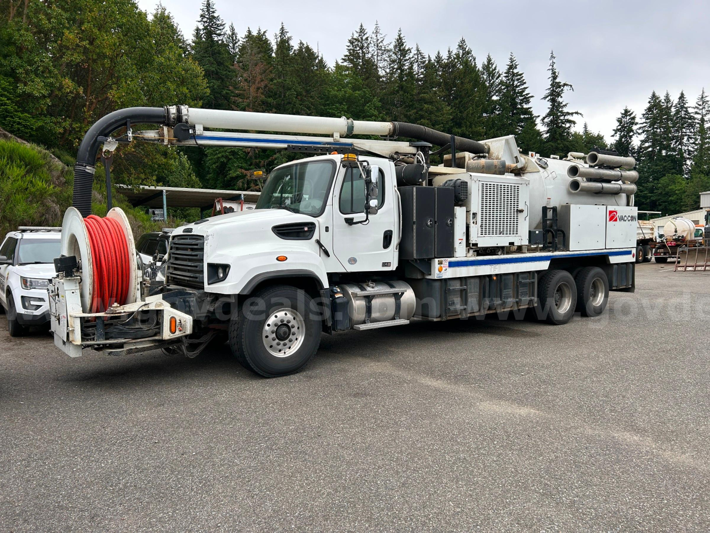 Truck-mounted vacuum unit with large reel of hose on the front, white cab, and industrial equipment on the rear chassis; Freightliner 2016 1114SD