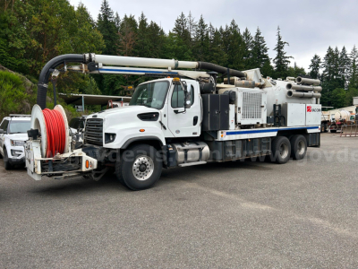 Truck-mounted vacuum unit with large reel of hose on the front, white cab, and industrial equipment on the rear chassis; Freightliner 2016 1114SD