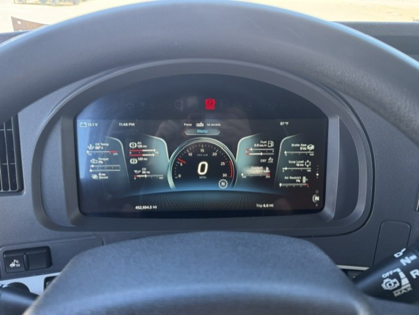 Kenworth T680 interior dashboard display showing digital gauges and speedometer in the center with surrounding data readouts.