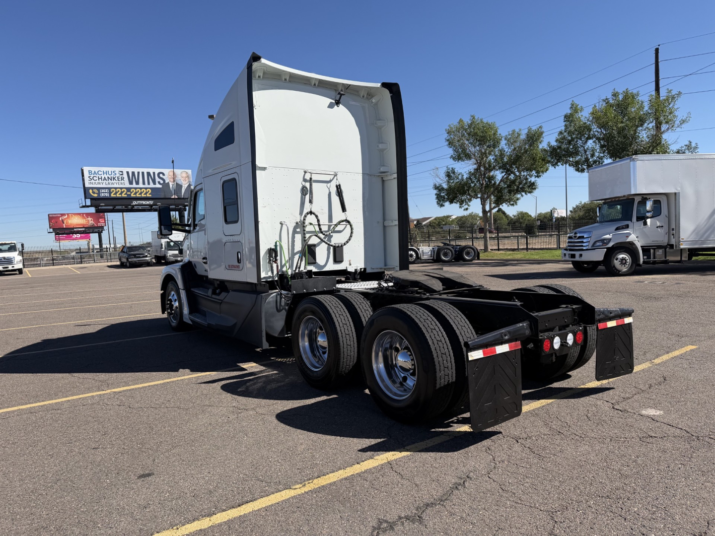 Kenworth T680 tractor chassis rear view showing fifth wheel and dual rear axles, sleeper cab rear, chrome wheels, and mud flaps.