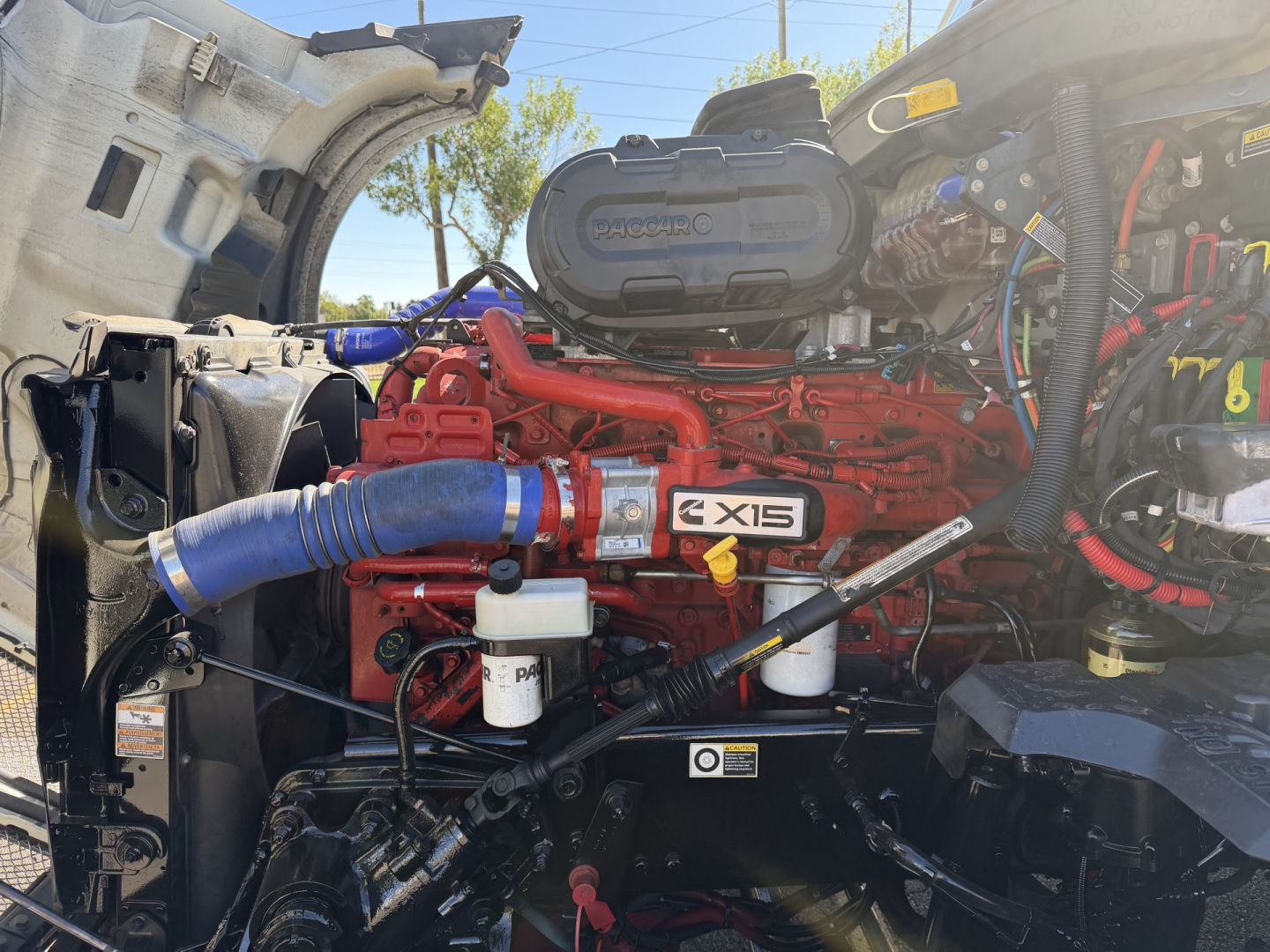 Kenworth T680 engine bay showing Cummins X15 engine and various hoses and components.