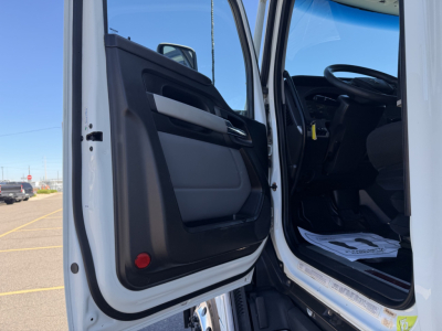 Kenworth T680 cab interior door area and open driver door showing steering wheel and floor mats.