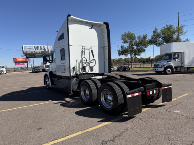 Kenworth T680 tractor chassis rear view showing fifth wheel and dual rear axles, sleeper cab rear, chrome wheels, and mud flaps.