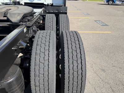 Twin rear tires of a 2022 Kenworth T680 truck chassis viewed from the side, showing dual tire arrangement and part of frame.