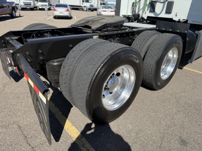 Dual rear axle on Kenworth truck chassis showing rear wheels and fuel tanks, with frame and suspension components visible.