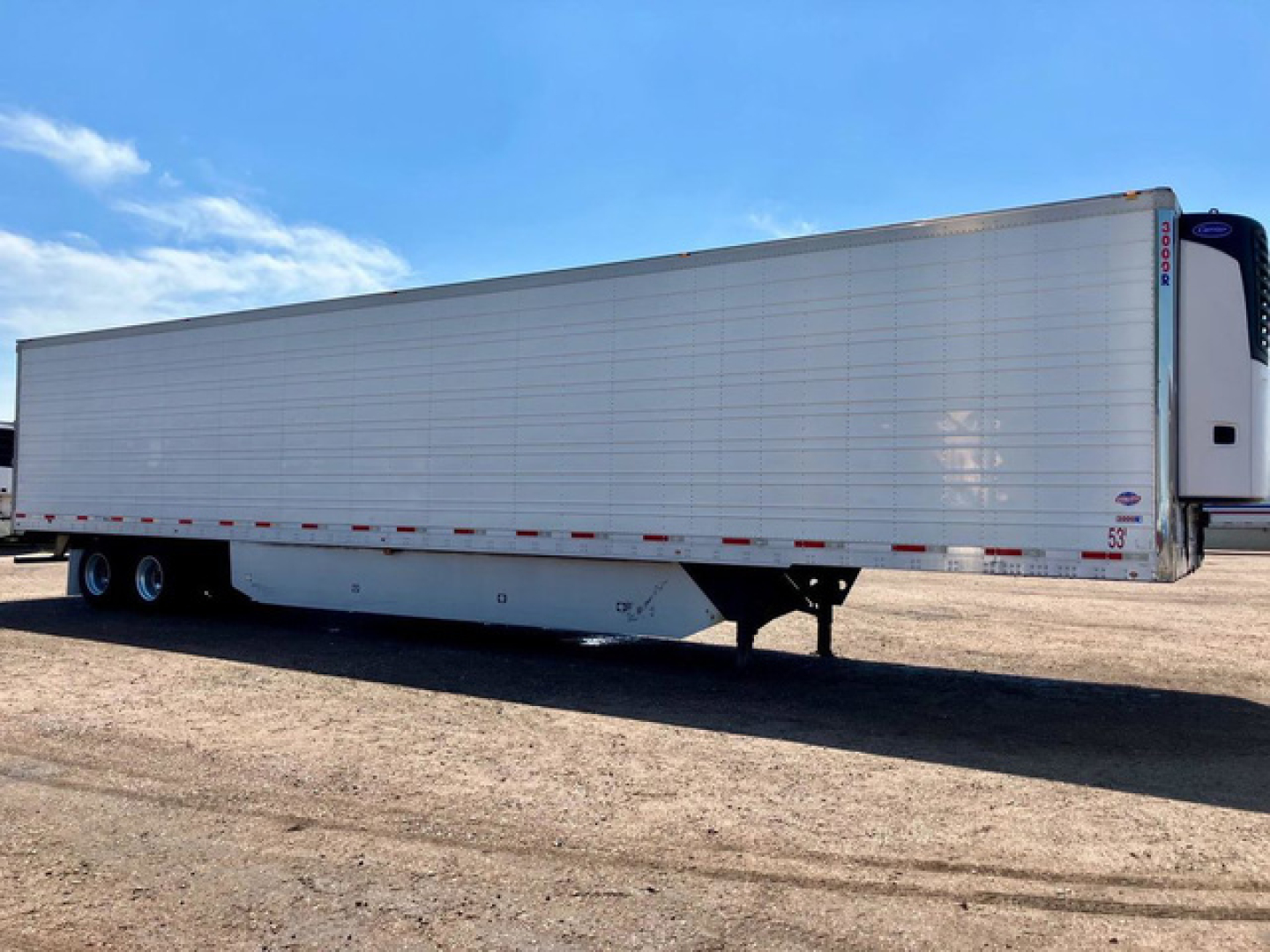 Utility reefer trailer side view showing long refrigerated box with landing gear and dual rear wheels.