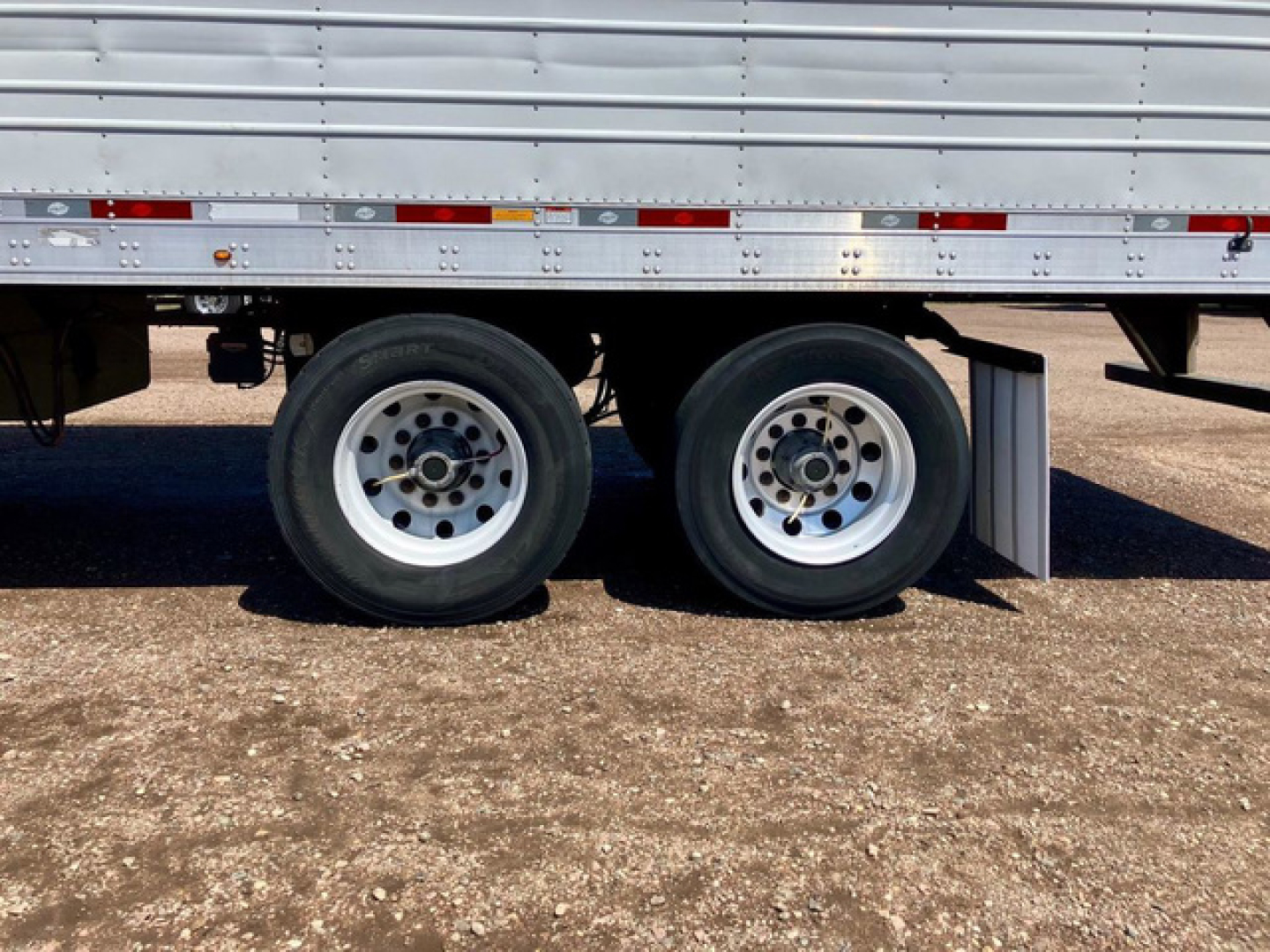Trailer wheels and lower side of a 2017 Utility Reefer trailer showing dual rear axles and lower side rail with reflective tape.
