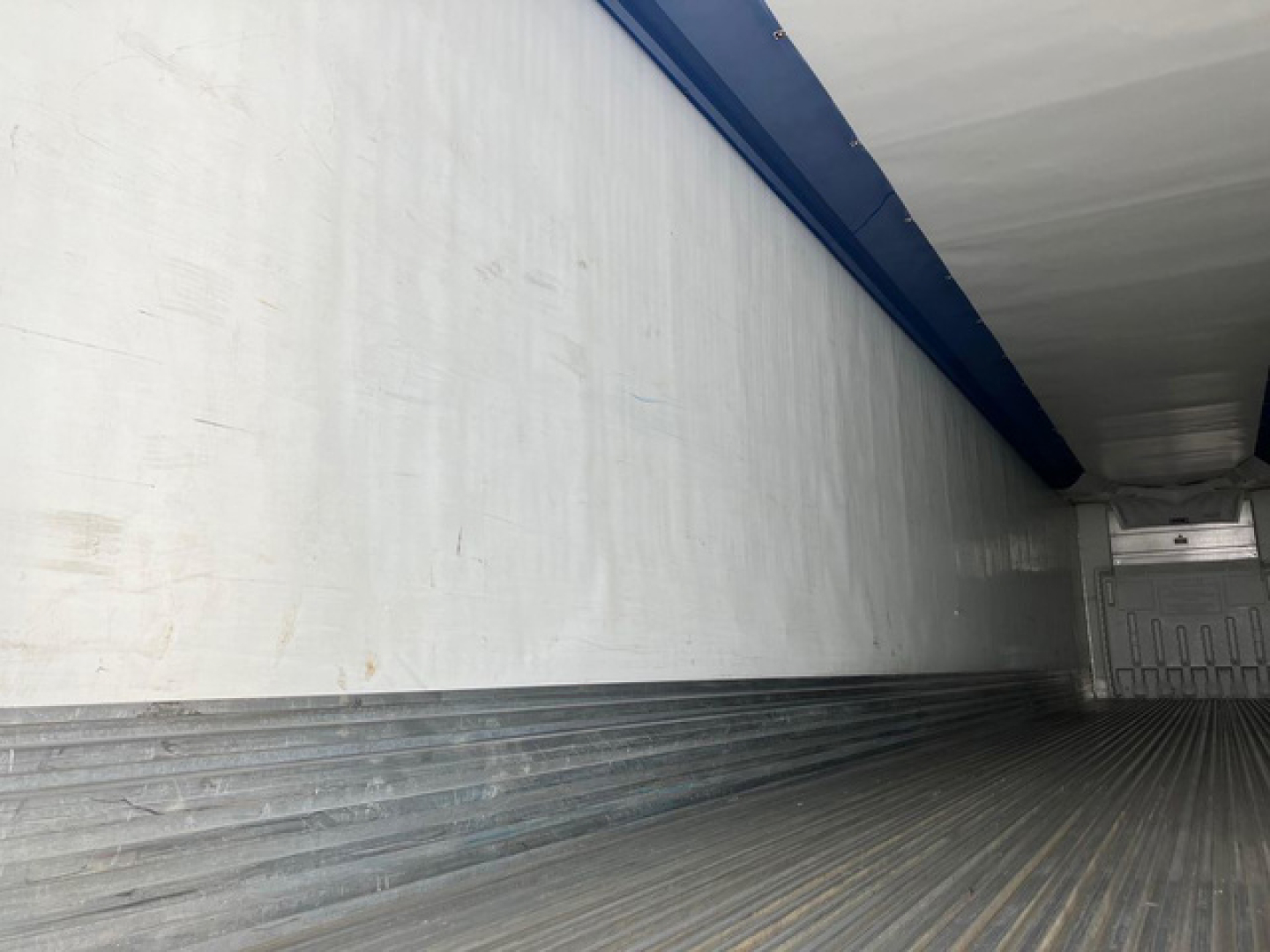 Trailer interior showing empty refrigerated cargo space with ribbed metal floor and curved side walls.