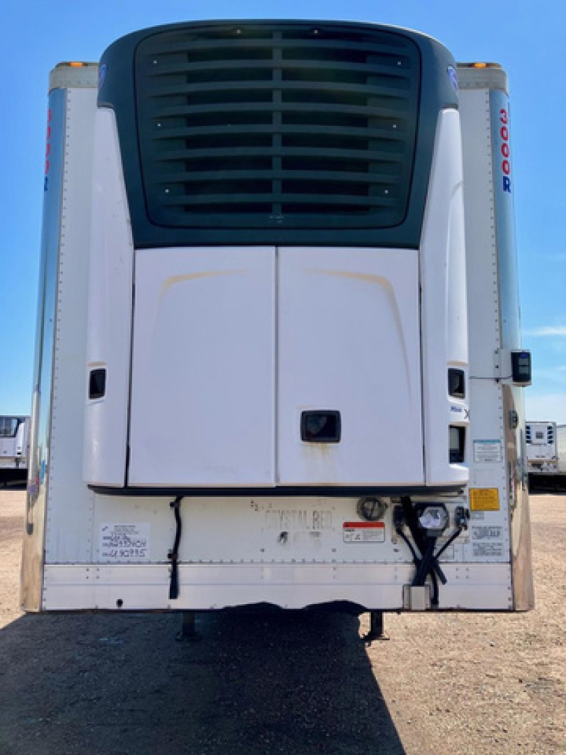 Rear view of a 2017 Utility reefer trailer showing the unit’s black radiator grille and white body, with red-orange reflective markers and a bumper with a chain and labels.
