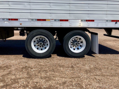 Trailer wheels and lower side of a 2017 Utility Reefer trailer showing dual rear axles and lower side rail with reflective tape.