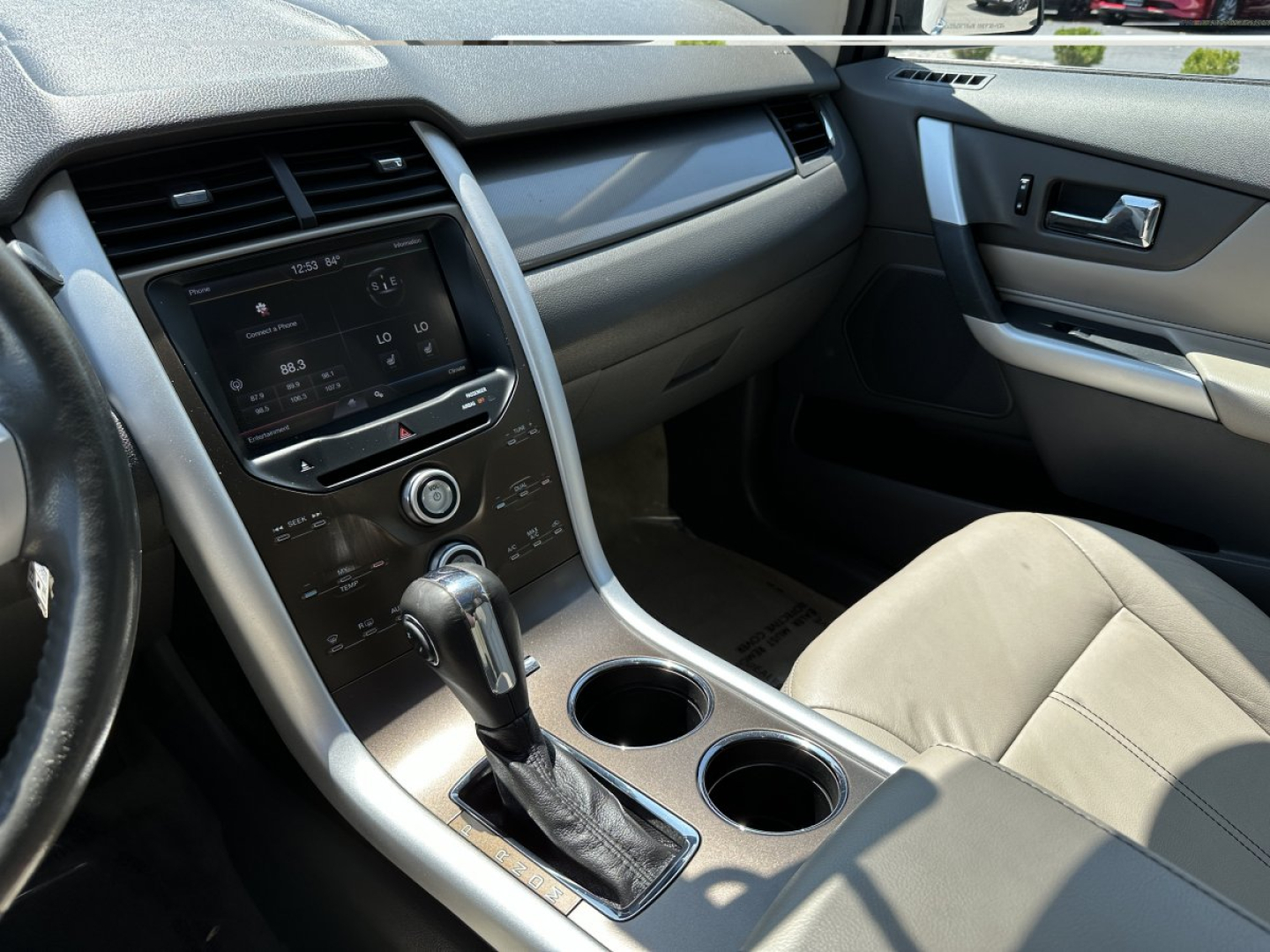Ford Edge interior view showing center console with gear shifter, cup holders, and infotainment display.