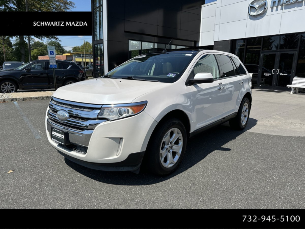 Ford Edge SUV white front three-quarter view showing chrome grille and Ford emblem, dealership lot in background.