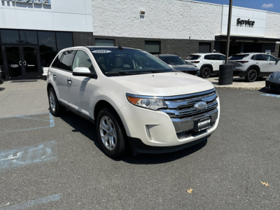 2011 Ford Edge white SUV in dealership lot, front three-quarter view showing chrome grille, headlights, and Ford emblem.
