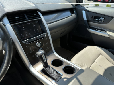 Ford Edge interior view showing center console with gear shifter, cup holders, and infotainment display.