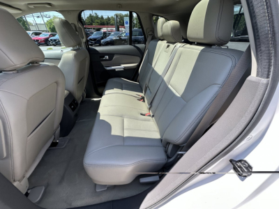 Ford Edge interior rear seat view showing light gray leather seats and rear door panel.