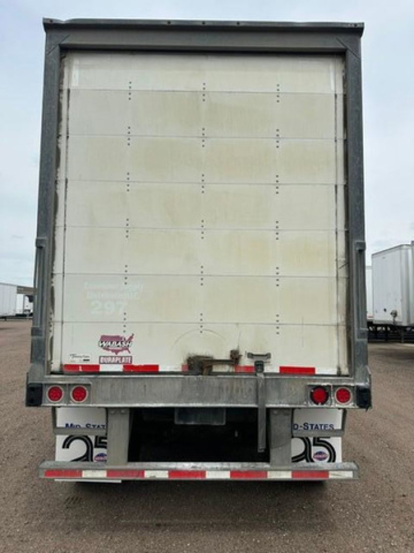 Rear view of a 2016 Wabash van trailer showing a tall vertical white cargo door with metal frame, rear bumper, red brake lights, and bumper reflectors. Visible stickers include a Durapak logo and a small number plate.