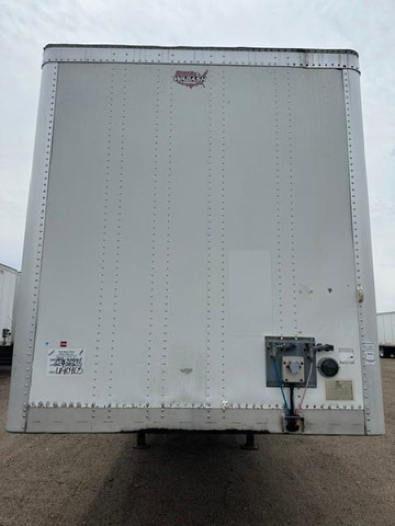 Rear view of a 2016 Wabash van trailer with a white exterior, riveted metal panels, and a small access panel near the lower right with utility connections.