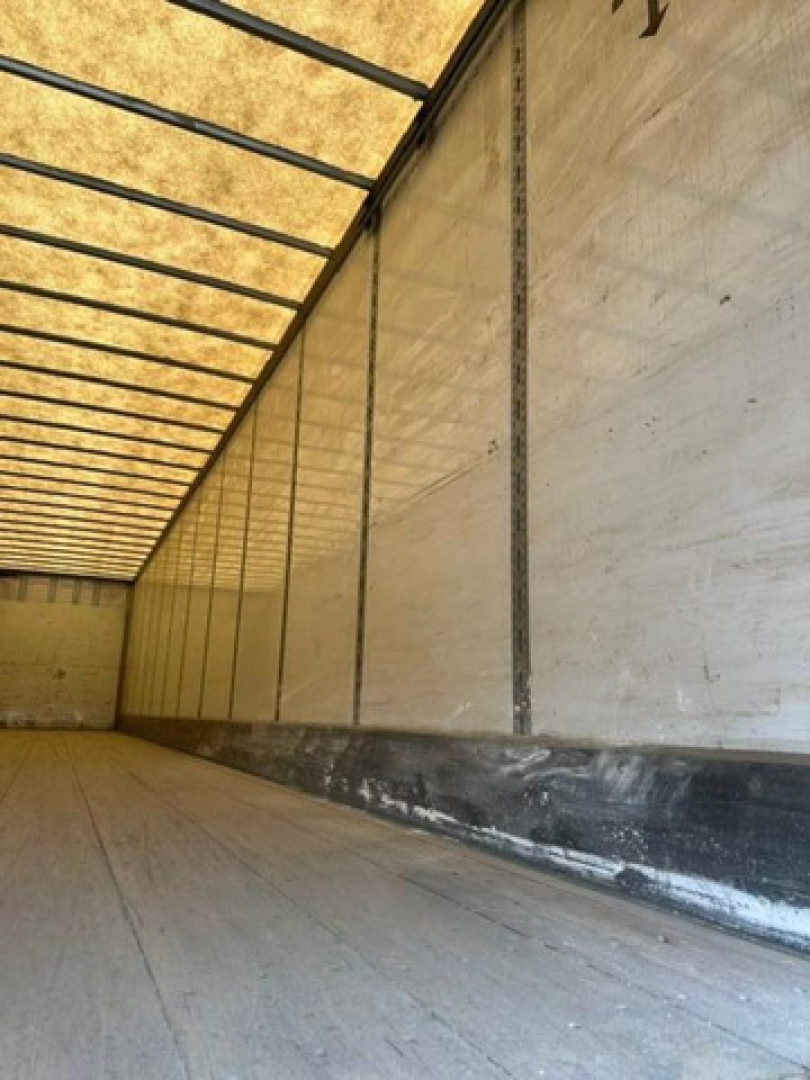 Trailer interior showing long empty cargo area with aluminum walls, vertical corner posts, and ribbed ceiling.
