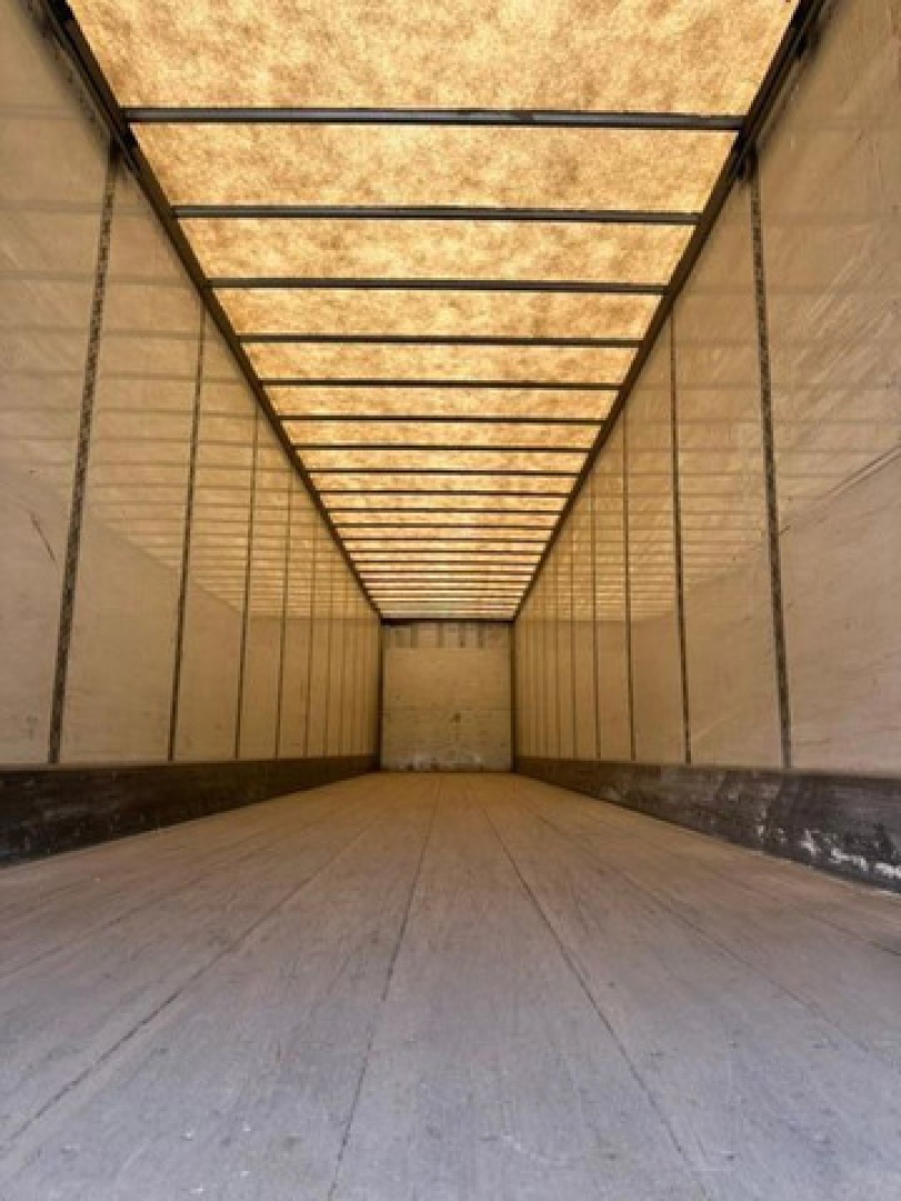 Trailer interior: empty Wabash van trailer with wooden ceiling panels and metal side walls, long empty cargo space.