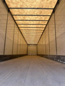 Trailer interior: empty Wabash van trailer with wooden ceiling panels and metal side walls, long empty cargo space.