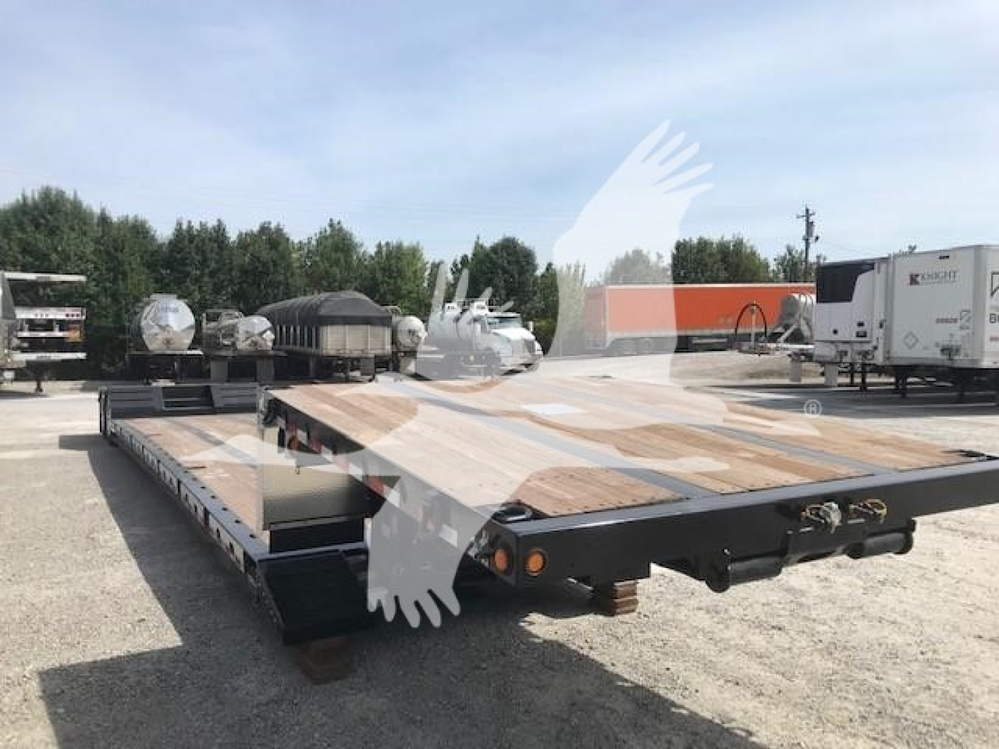 Lowboy trailer showing flat deck with wooden boards and black steel frame, rear lights, and extendable neck area.